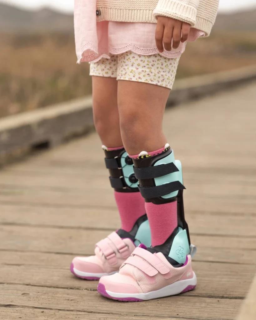 Man sieht die Beine von einem Kind, welches die neue proprio AFO Spring trägt. Sie hat ebenso rosa Turnschuhe an.