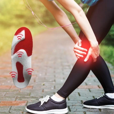 A woman is holing her knee, because she is in pain. She is outside running.